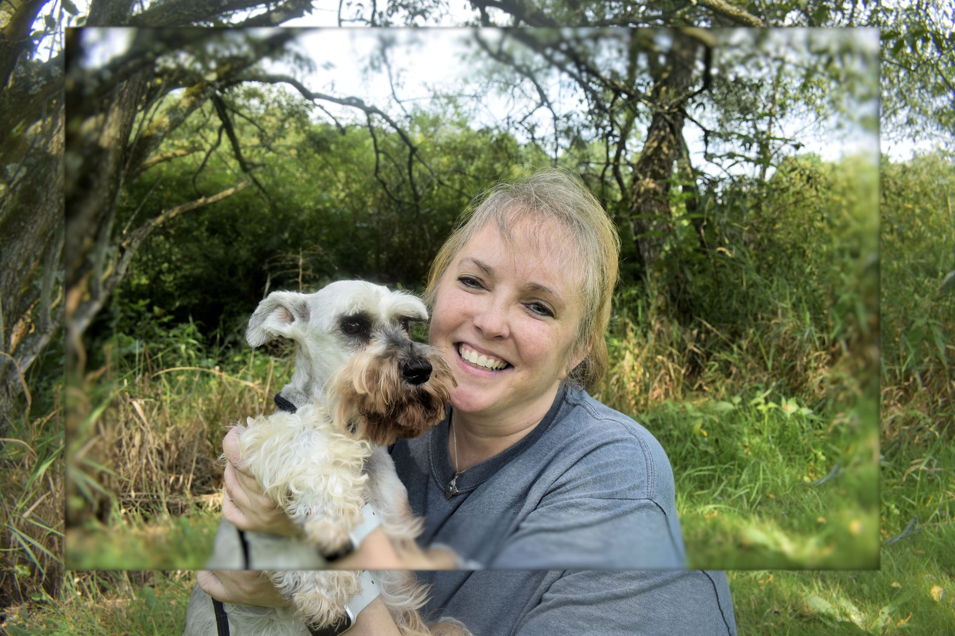 a woman is holding a small dog in her arms