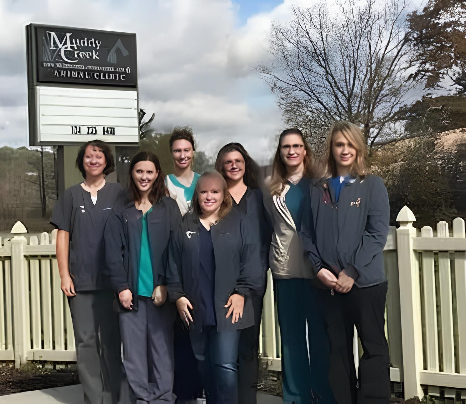 a group of women standing in front of a muddy creek dental clinic sign