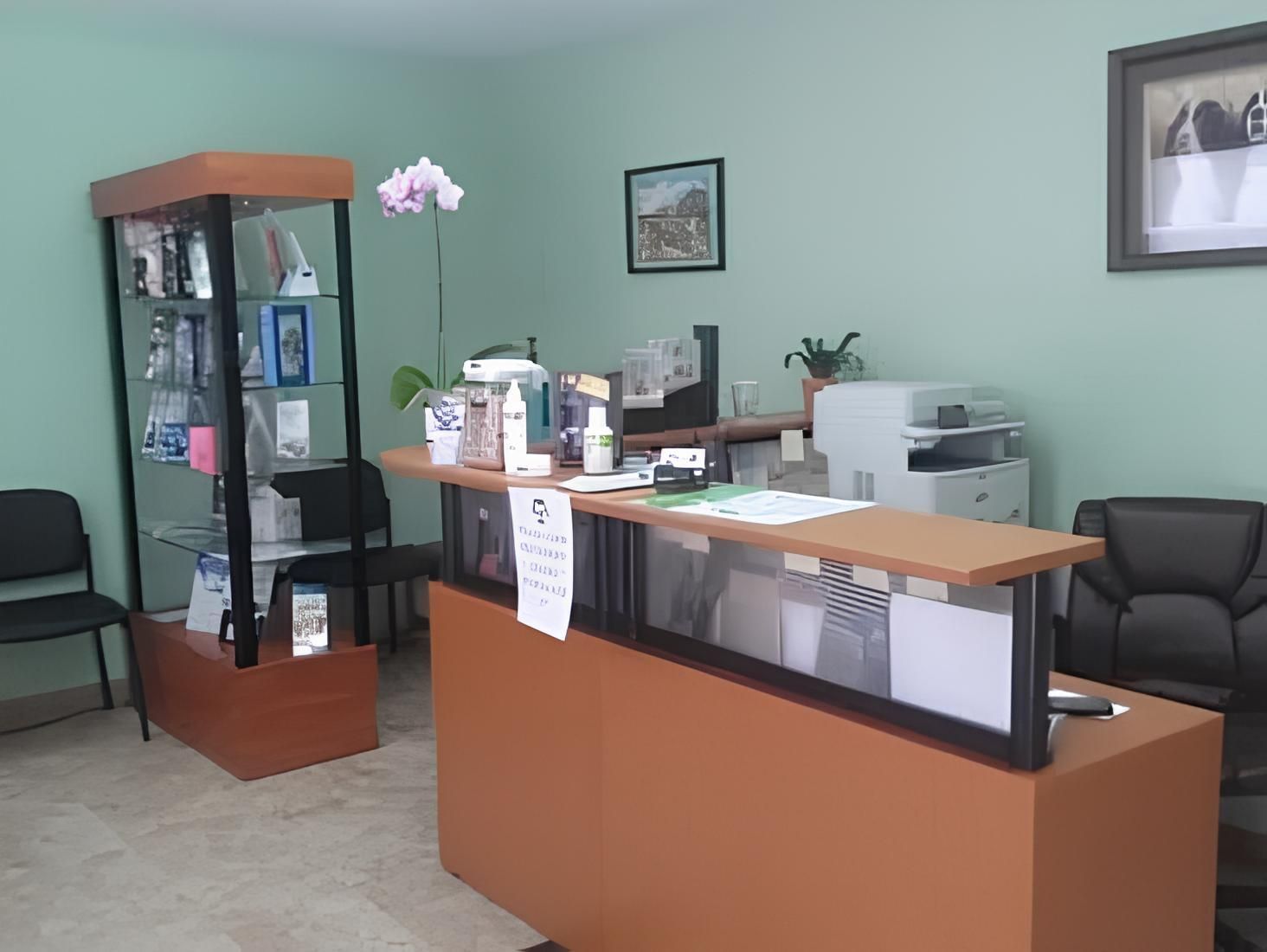 a waiting room with a desk, chairs, a display case and a picture on the wall