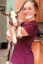 a woman is holding a baby goat in her arms .