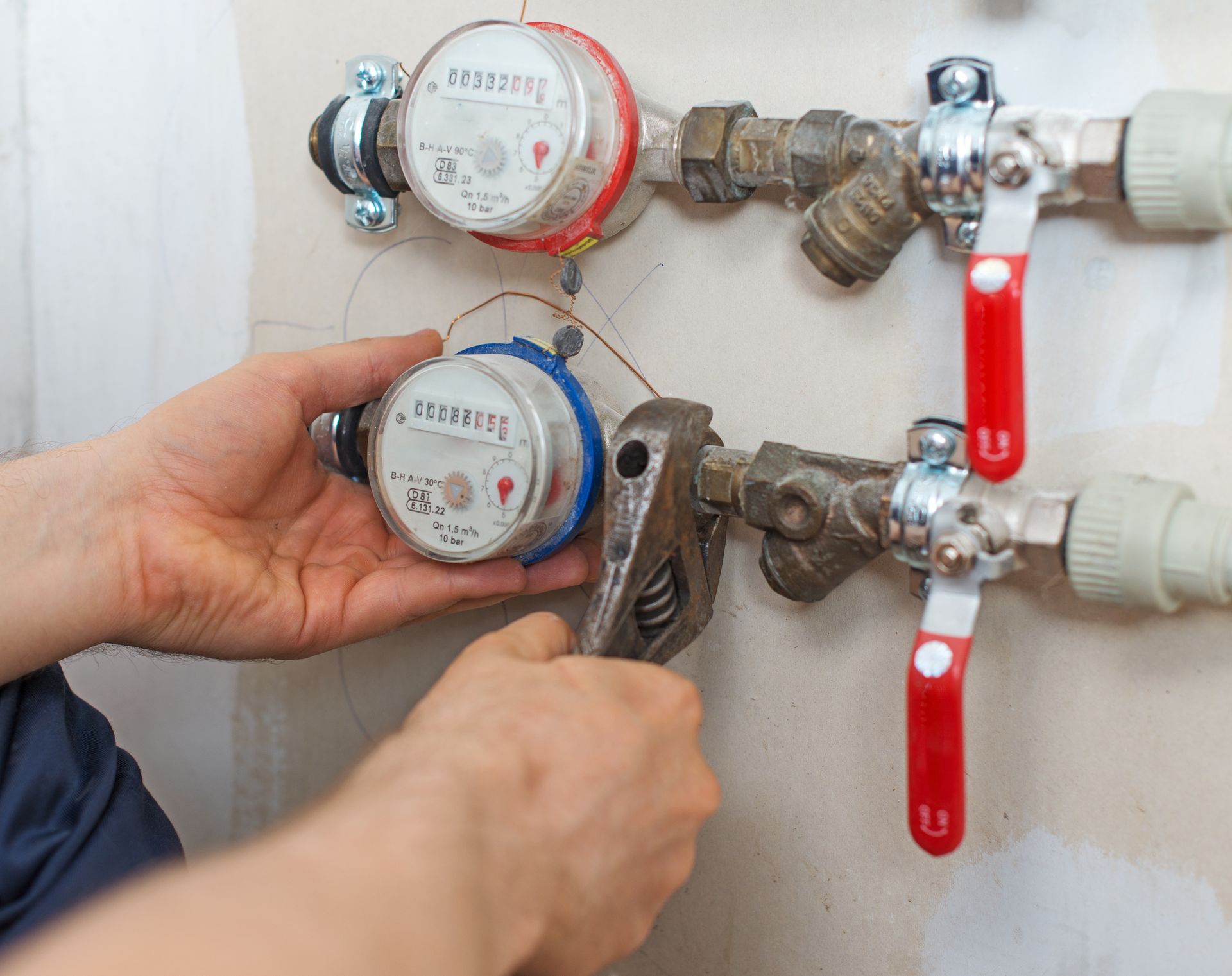 A man is fixing a water meter with a wrench.