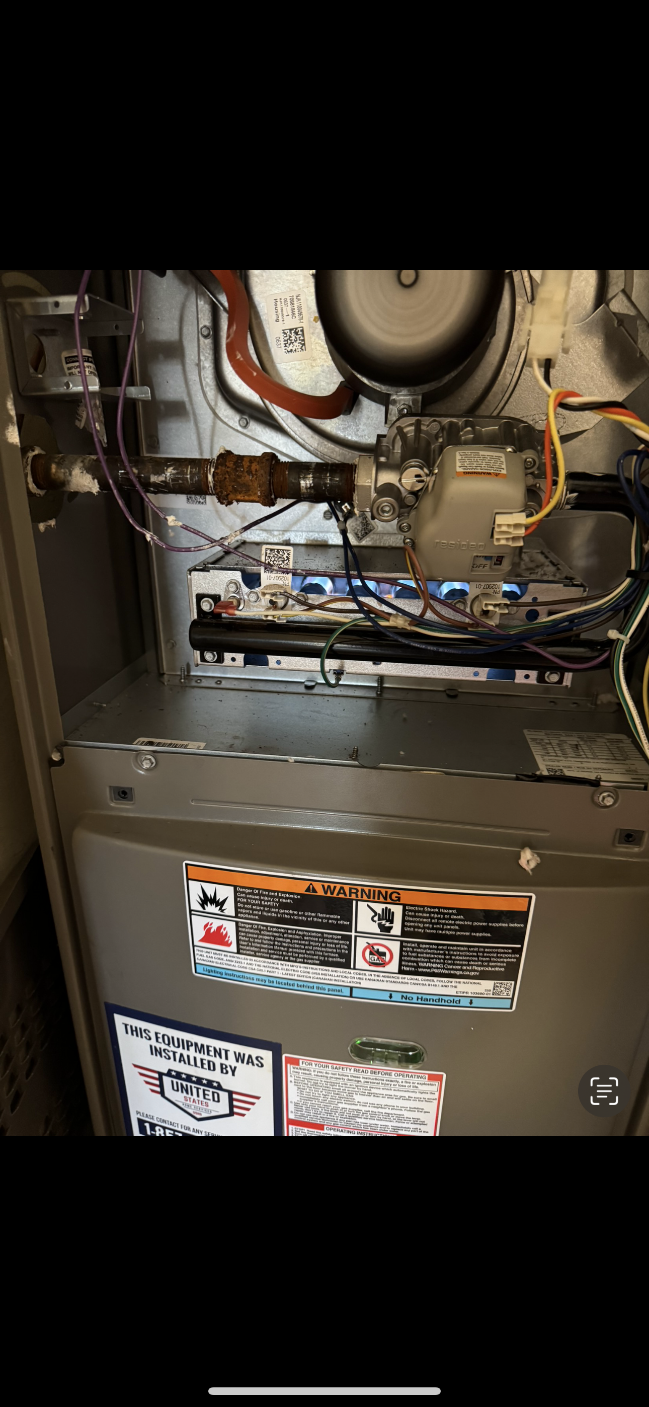 Furnace unit inside a closet with ductwork and connected wires.