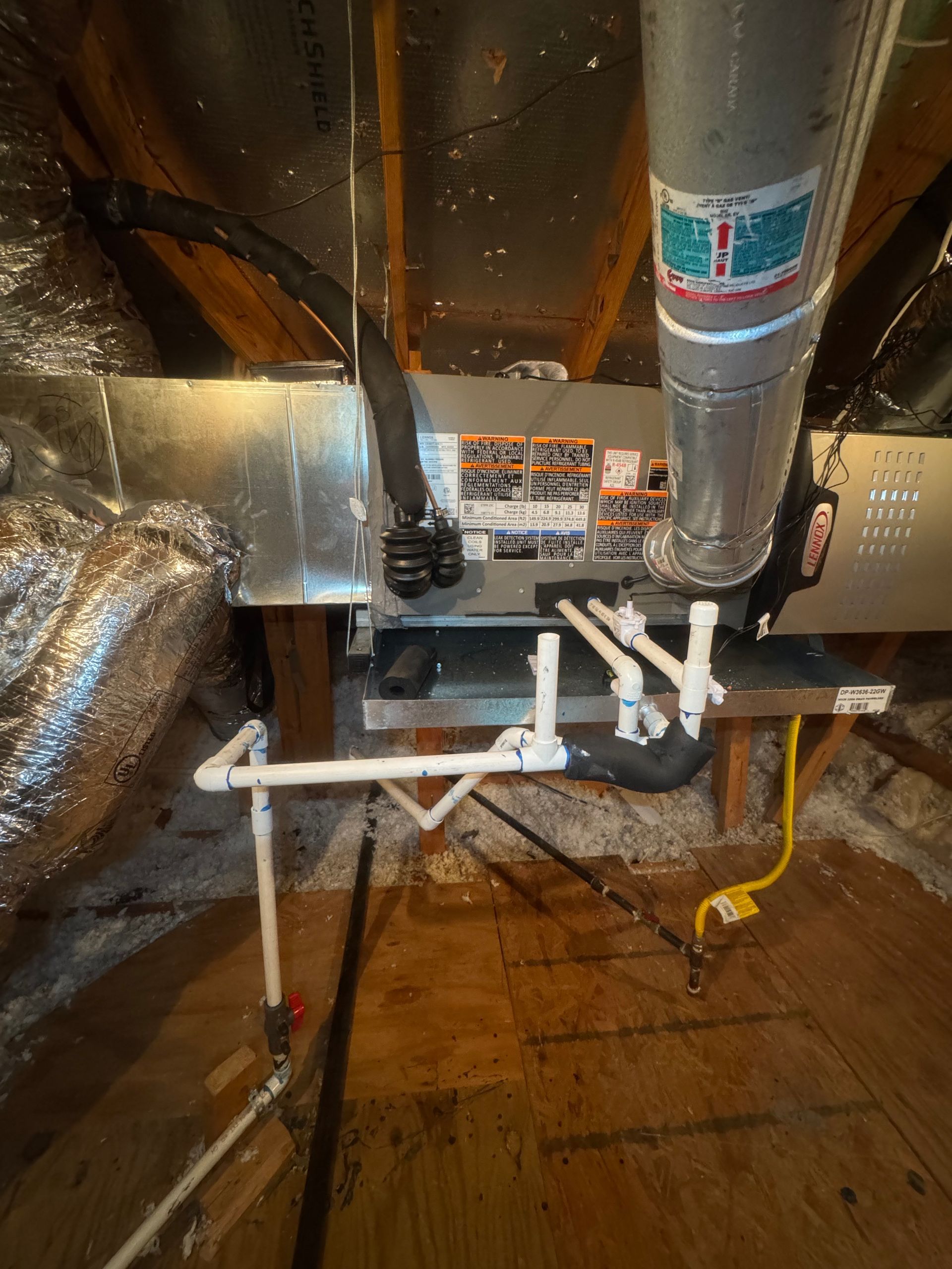 Two air conditioning units on a concrete pad next to a brick wall and a fence. Tools and a box are in front.