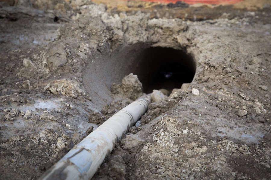 A pipe being pushed through a hole in the dirt, likely for underground utilities.