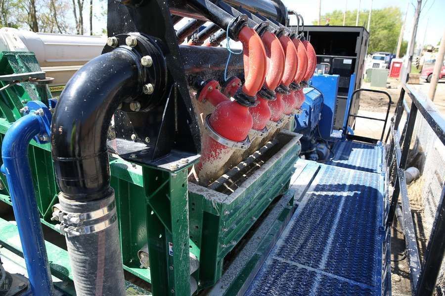 Close-up of industrial equipment with black pipes, red cones, and a green frame on a metal platform.