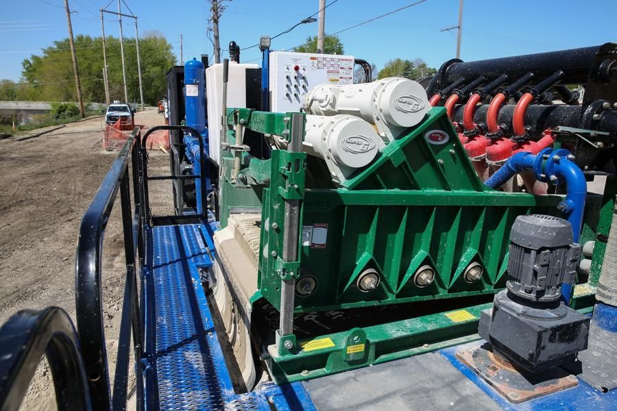 A mobile industrial water filtration unit on a gravel surface, featuring green and blue components, pipes, and electrical panels.