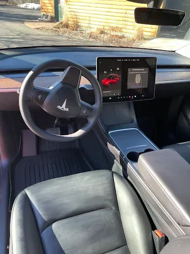 The interior of a tesla model 3 with a steering wheel and dashboard.