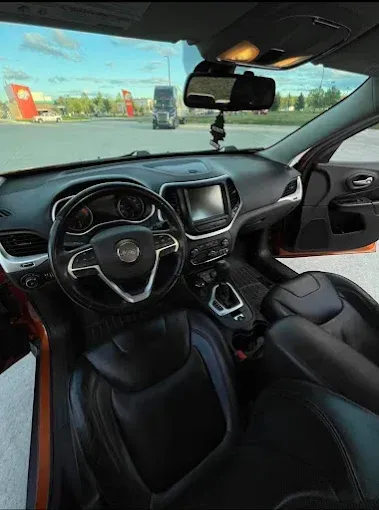 The interior of a jeep cherokee is shown with the door open.