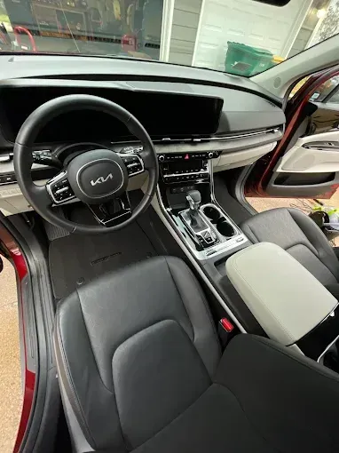 The interior of a red car with black seats and a steering wheel.