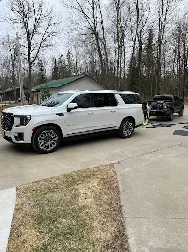 A white suv is parked in a driveway next to a black truck.