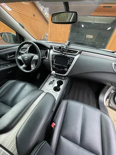 The interior of a nissan murano with black leather seats and a steering wheel.