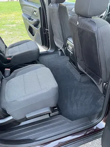 The inside of a car with the door open and the seats folded down.