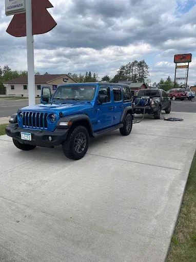 A blue jeep is parked on the side of the road next to another jeep.