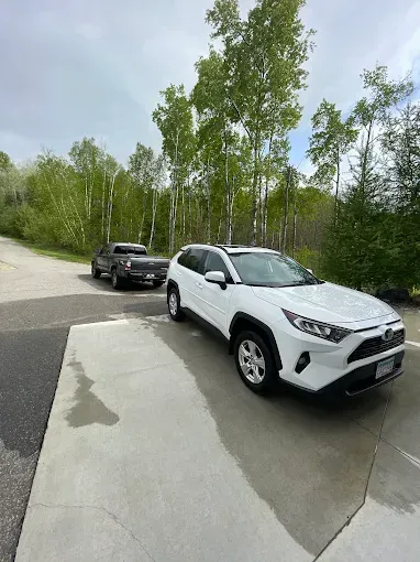 A white suv is parked in a parking lot next to a black truck.