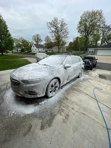 A car is covered in foam in a driveway.