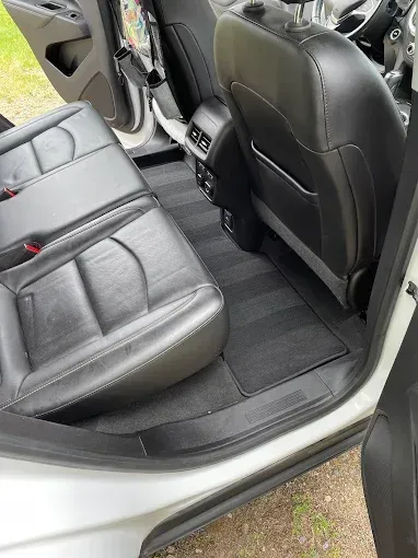 The back seat of a white car with the door open.
