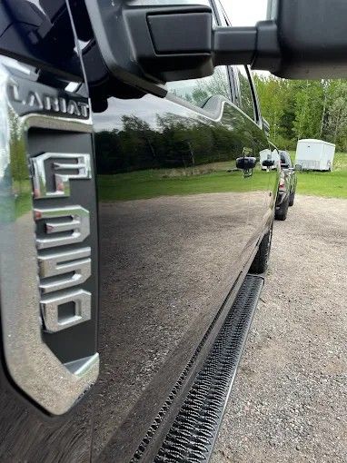 A black ford truck is parked in a gravel lot.