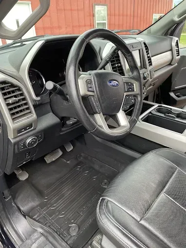 The interior of a ford truck with a steering wheel and seats.