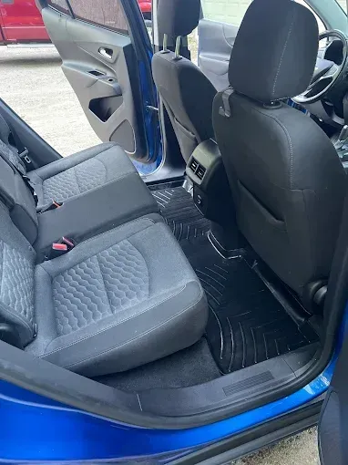 The inside of a blue car with the door open and black seats.