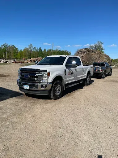 A white truck is parked in a dirt lot next to a black truck.