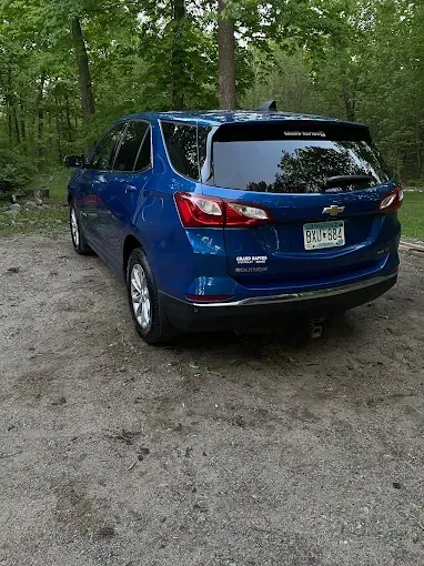 A blue chevrolet equinox is parked in a dirt lot.