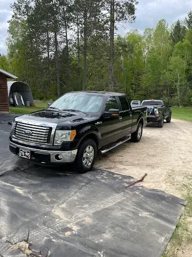 A black ford f150 pickup truck is parked in a driveway.