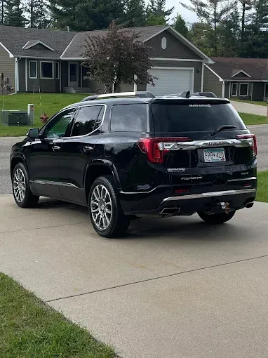 A black suv is parked in a driveway in front of a house.