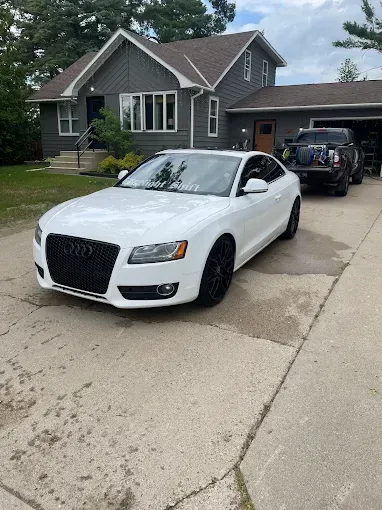 A white car is parked in front of a house.