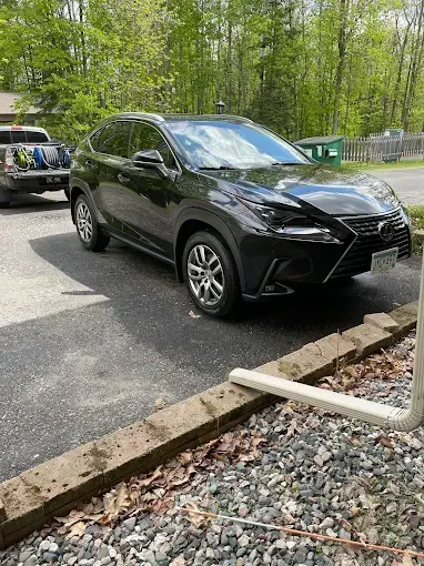 A black lexus nx is parked in a gravel lot.