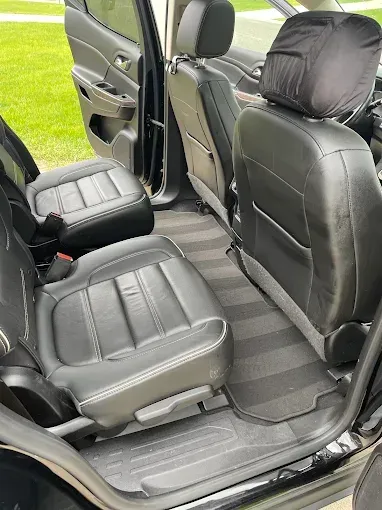 The interior of a black car with leather seats and a striped floor.