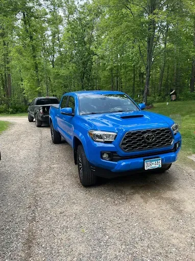 A blue toyota tacoma truck is parked on a gravel road.