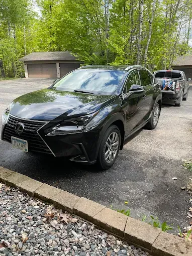 A black lexus nx is parked in a driveway next to a garage.