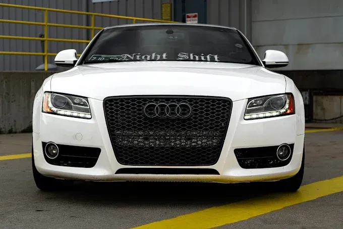 A white audi is parked in a parking lot