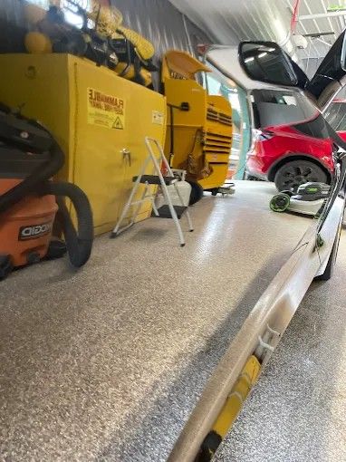 Showing ceramic coating job on a car. A garage with a white car, yellow cabinet, and open red car door. The floor is speckled.