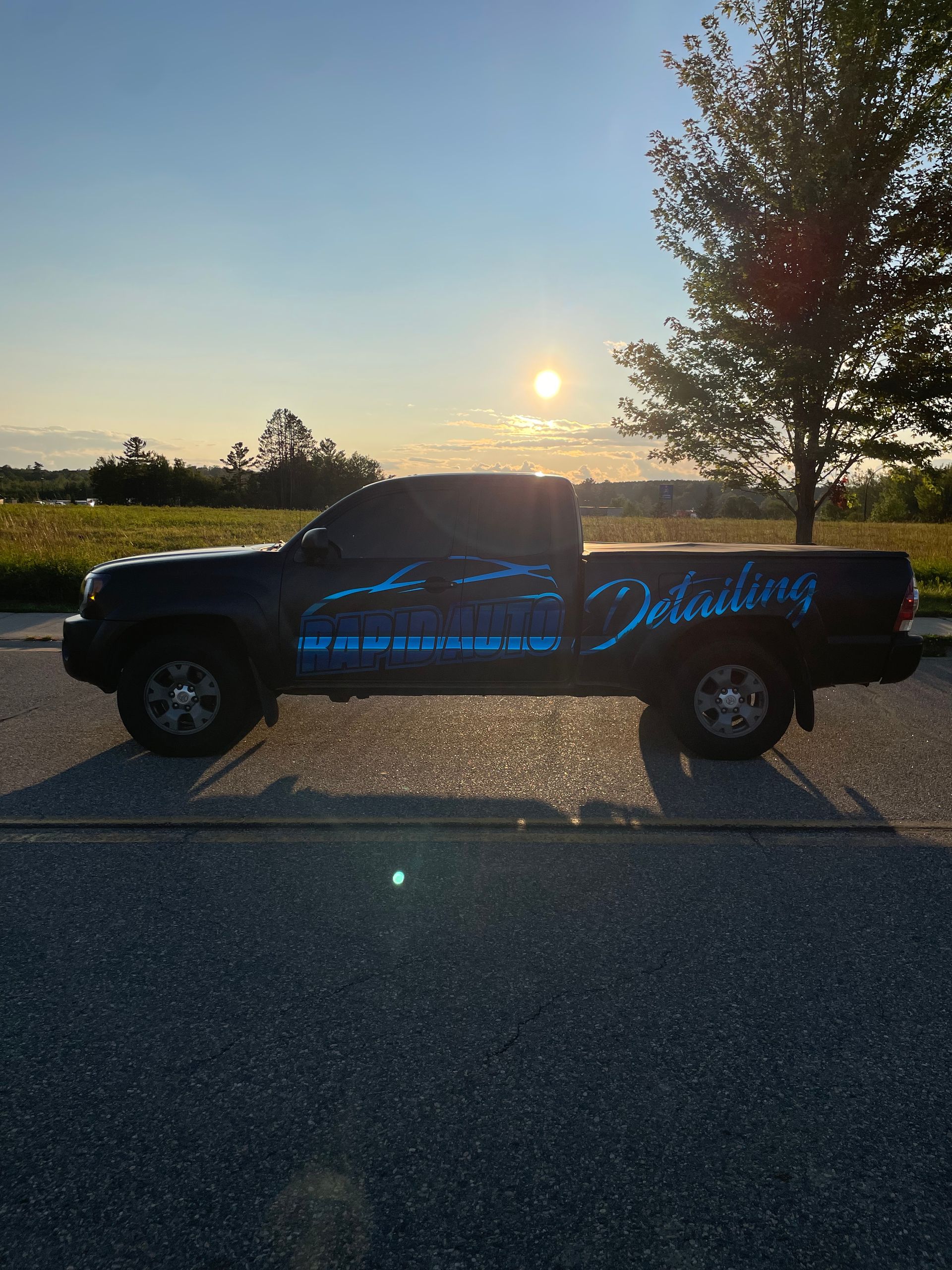 Black pickup truck with blue detailing logo parked on asphalt at sunrise.