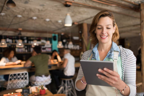 A woman is holding a tablet in a restaurant.