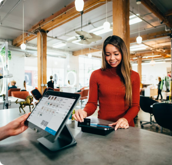 A woman in a red sweater is using a tablet at a counter.