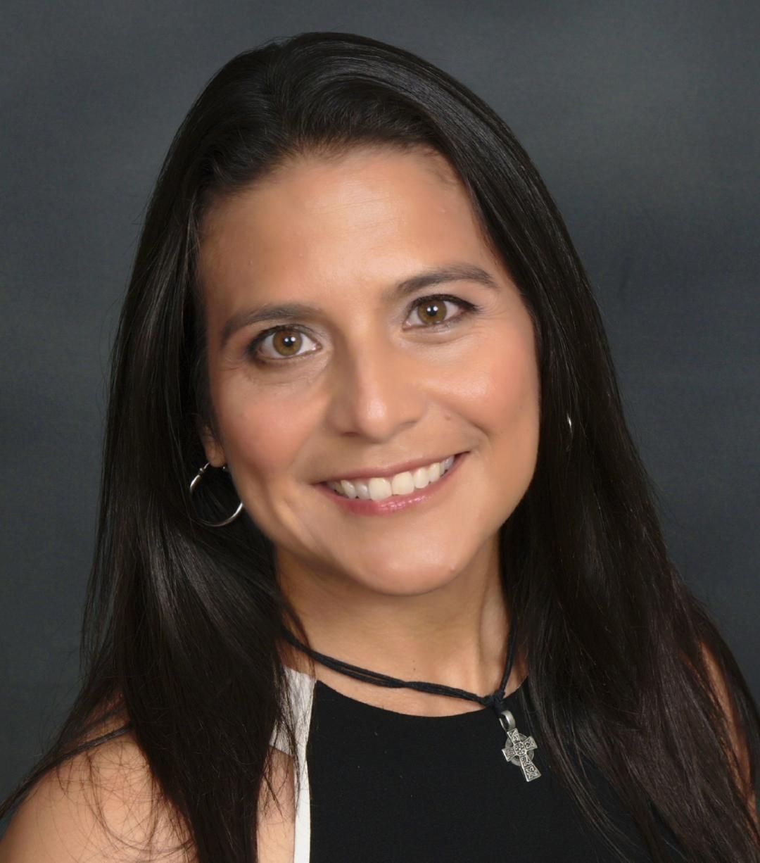 A woman with long dark hair is smiling for the camera