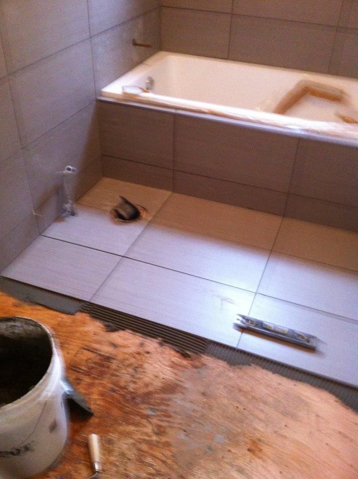 Une salle de bain avec une baignoire et un seau de ciment sur le sol