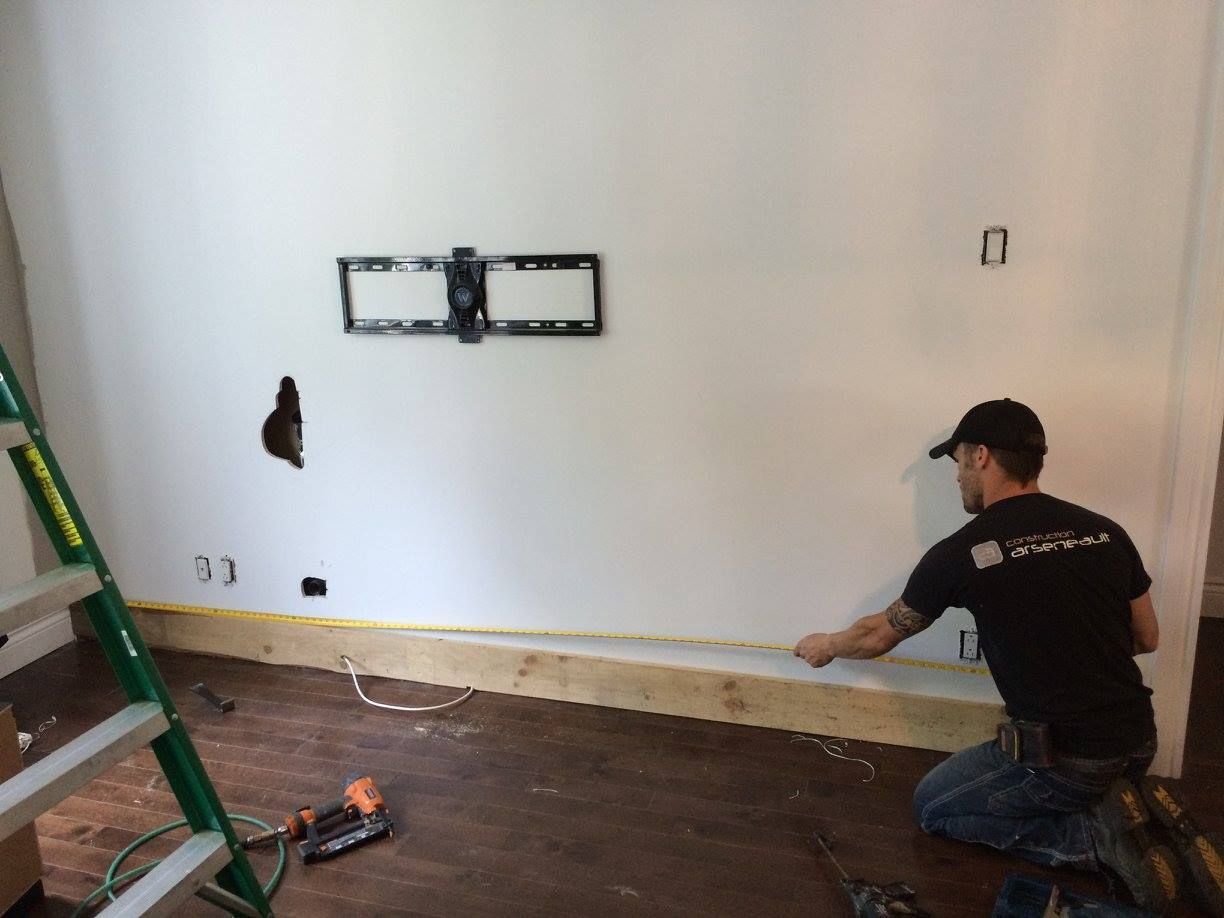 Un homme mesure un mur avec un ruban à mesurer.