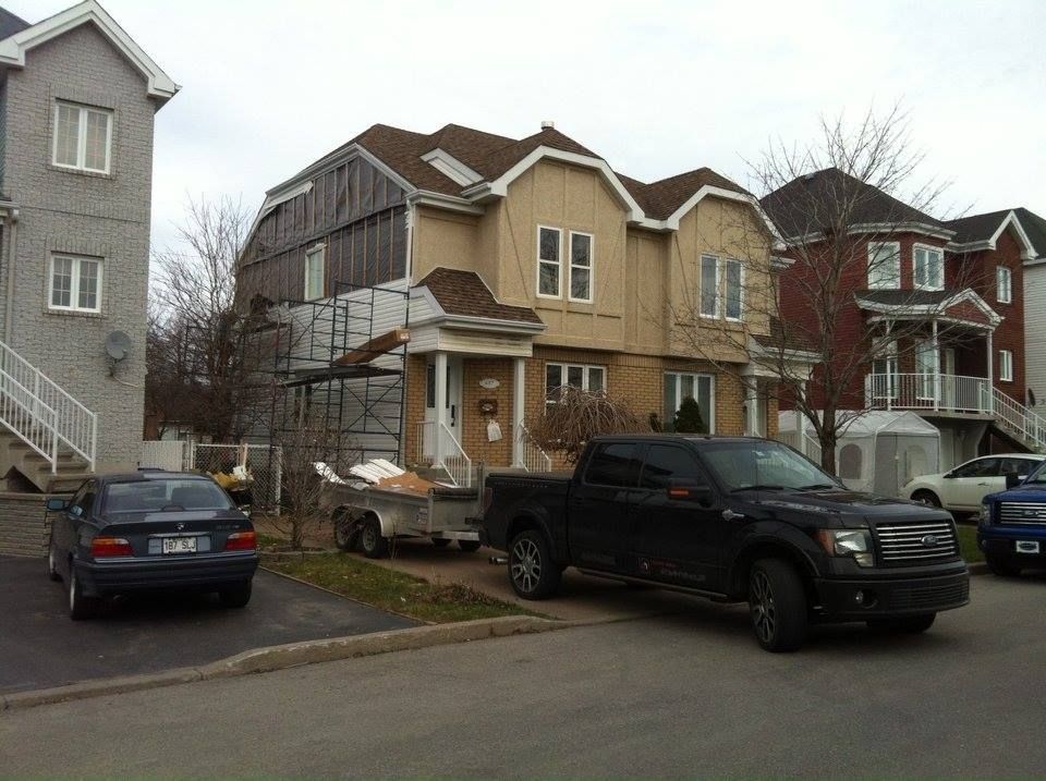 Un camion noir est garé devant une maison en construction.
