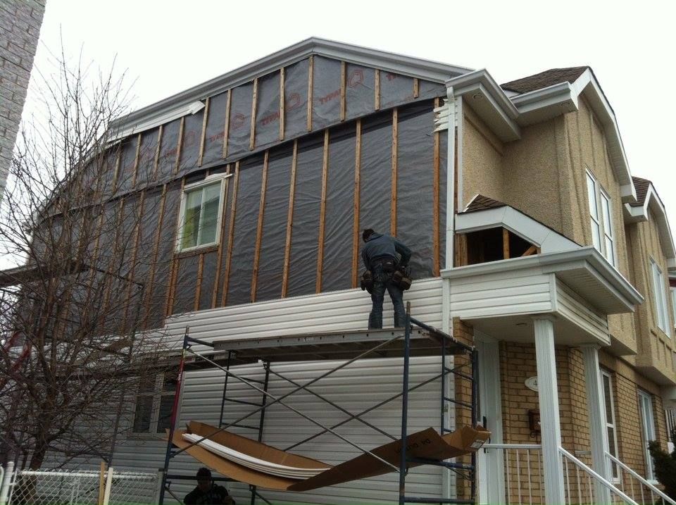 Un homme se tient sur un échafaudage sur le côté d'une maison.