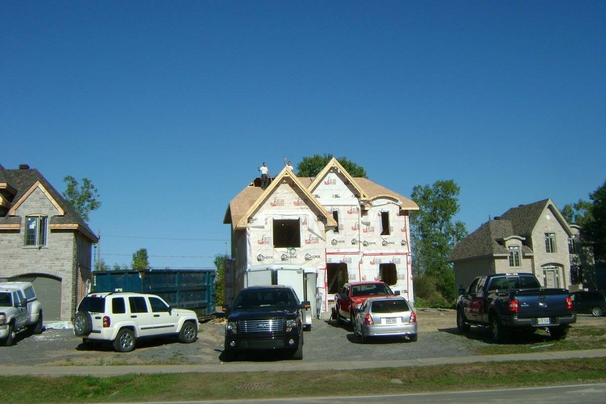 Une rangée de voitures est garée devant une maison en construction