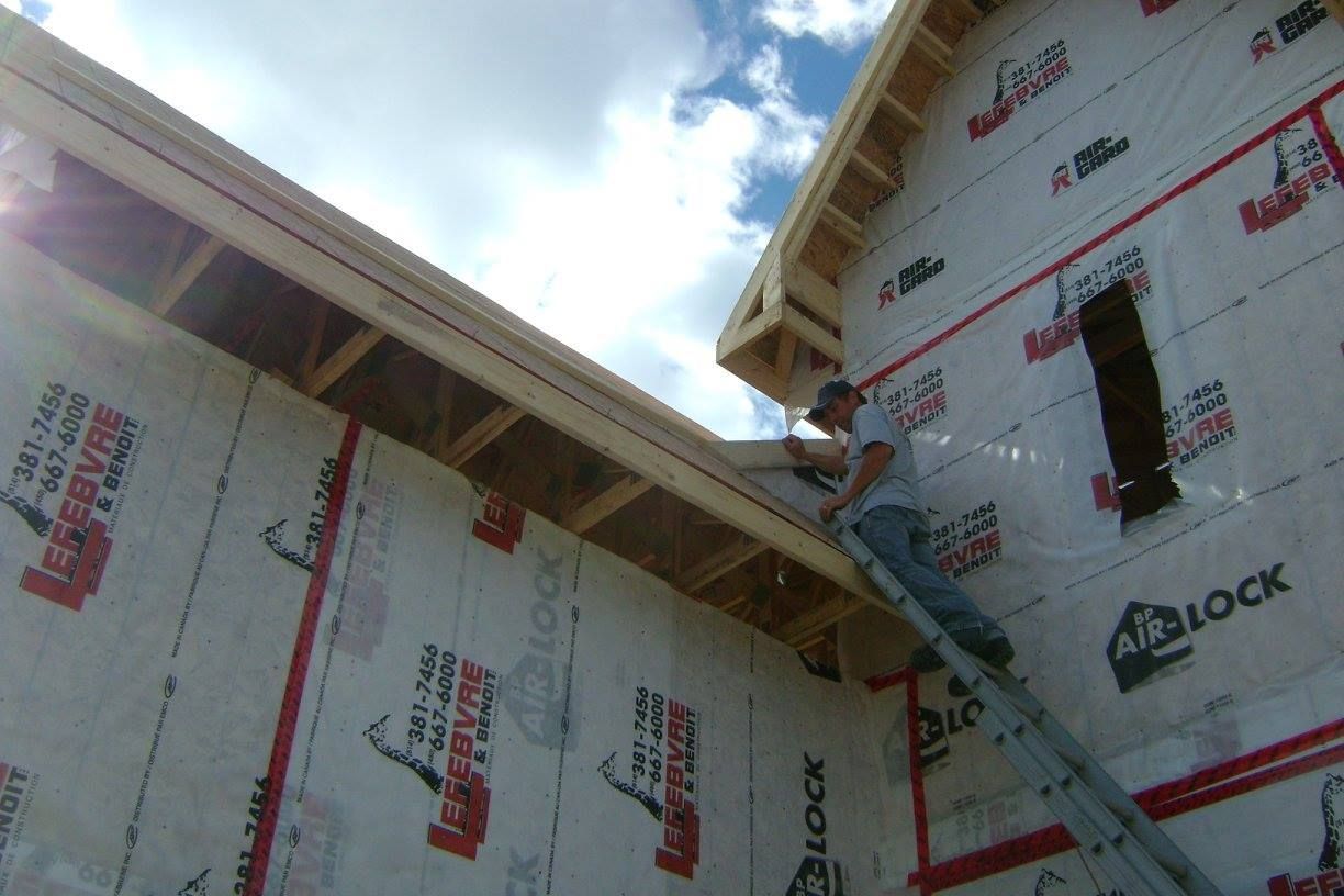 Un homme se tient sur une échelle sur le côté d'un bâtiment.