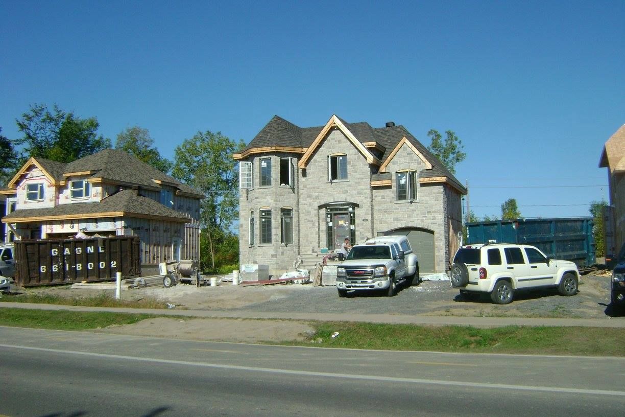 Une grande maison en construction avec des voitures garées devant