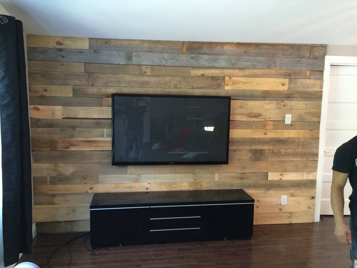 Un téléviseur à écran plat est monté sur un mur en bois dans un salon.