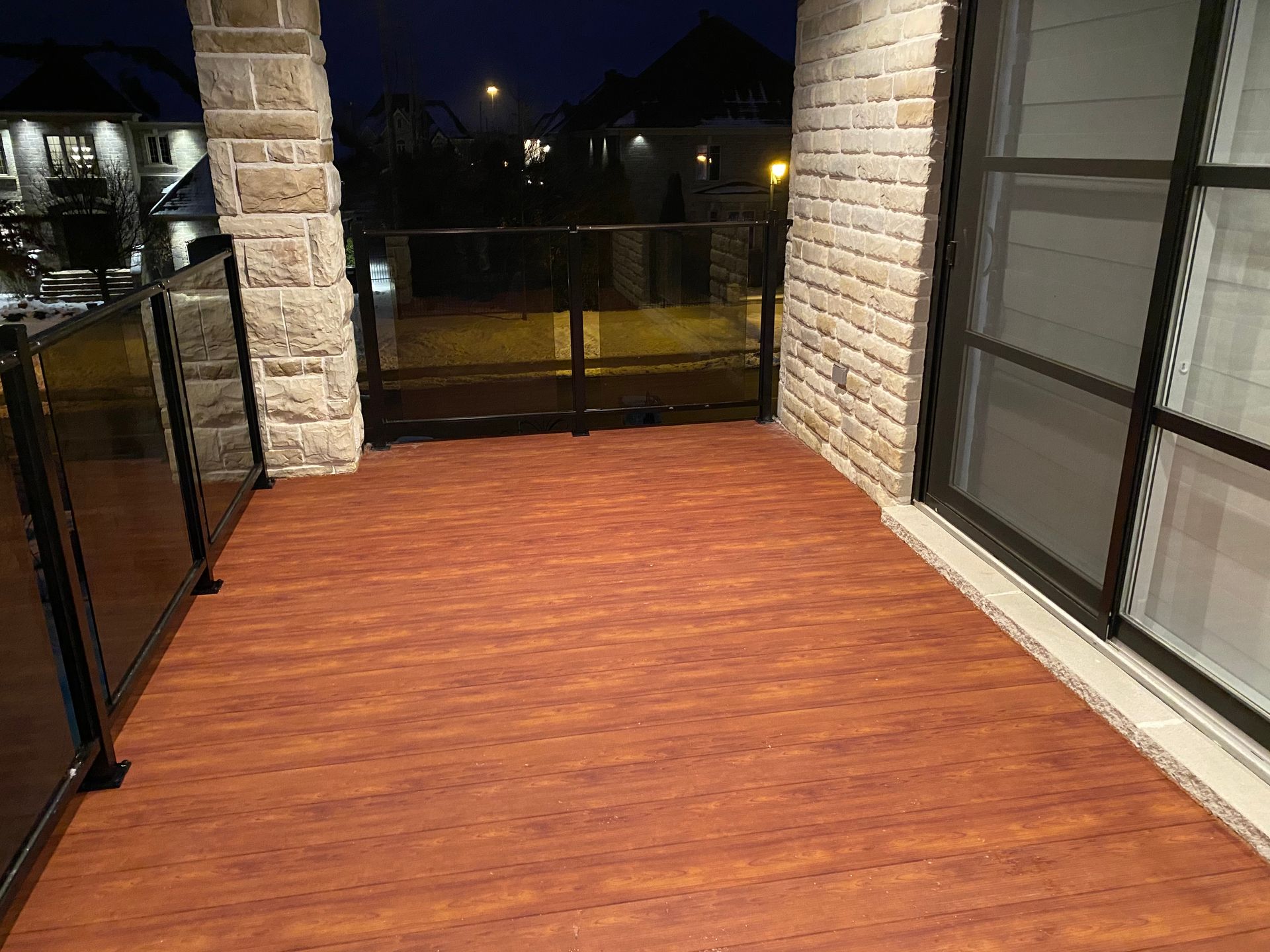 Un balcon avec un plancher en bois et un mur de briques la nuit.