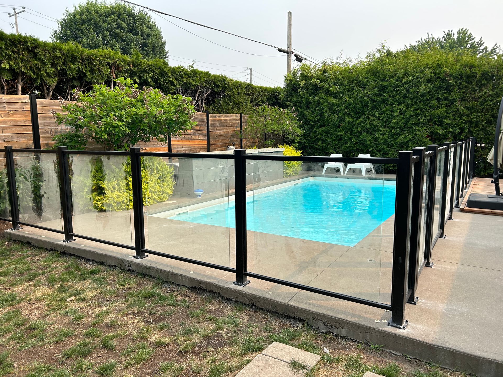 Une piscine entourée d'une clôture en verre dans une cour arrière.