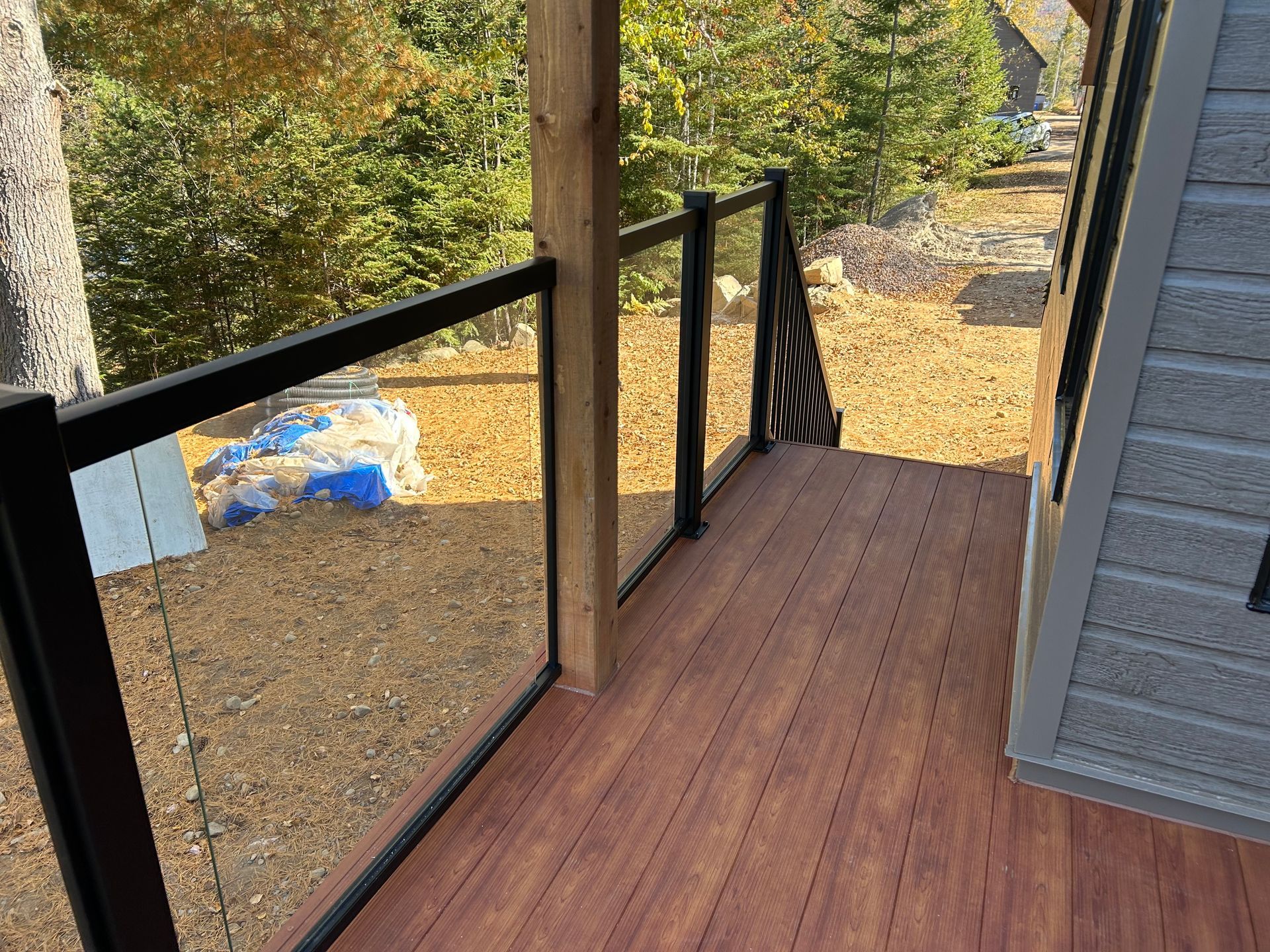 Une terrasse avec une balustrade en verre et un plancher en bois.