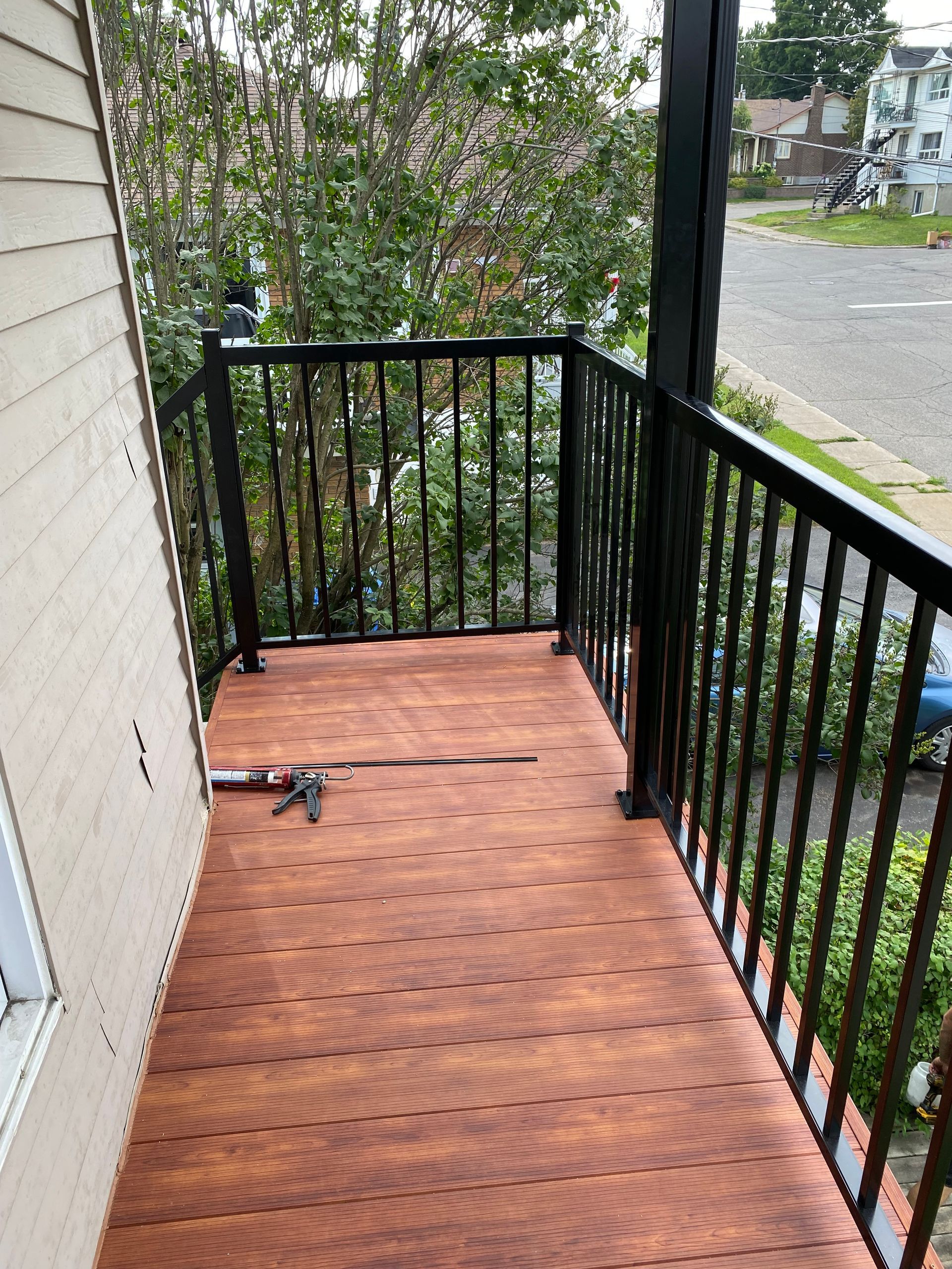 Un balcon avec une balustrade noire et un plancher en bois.